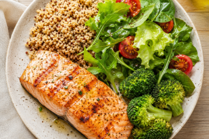 Prato saudável com salmão, quinoa e salada verde, rico em fibras e gorduras boas para o fígado.